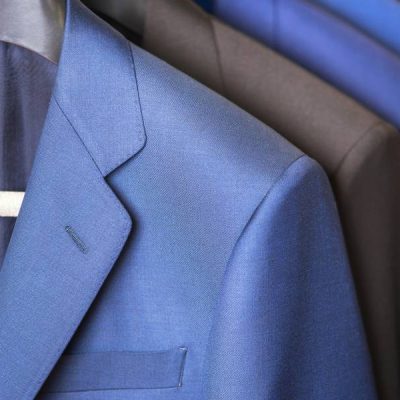 close up luxurious style gentlemen suit row, hanging in a closet .